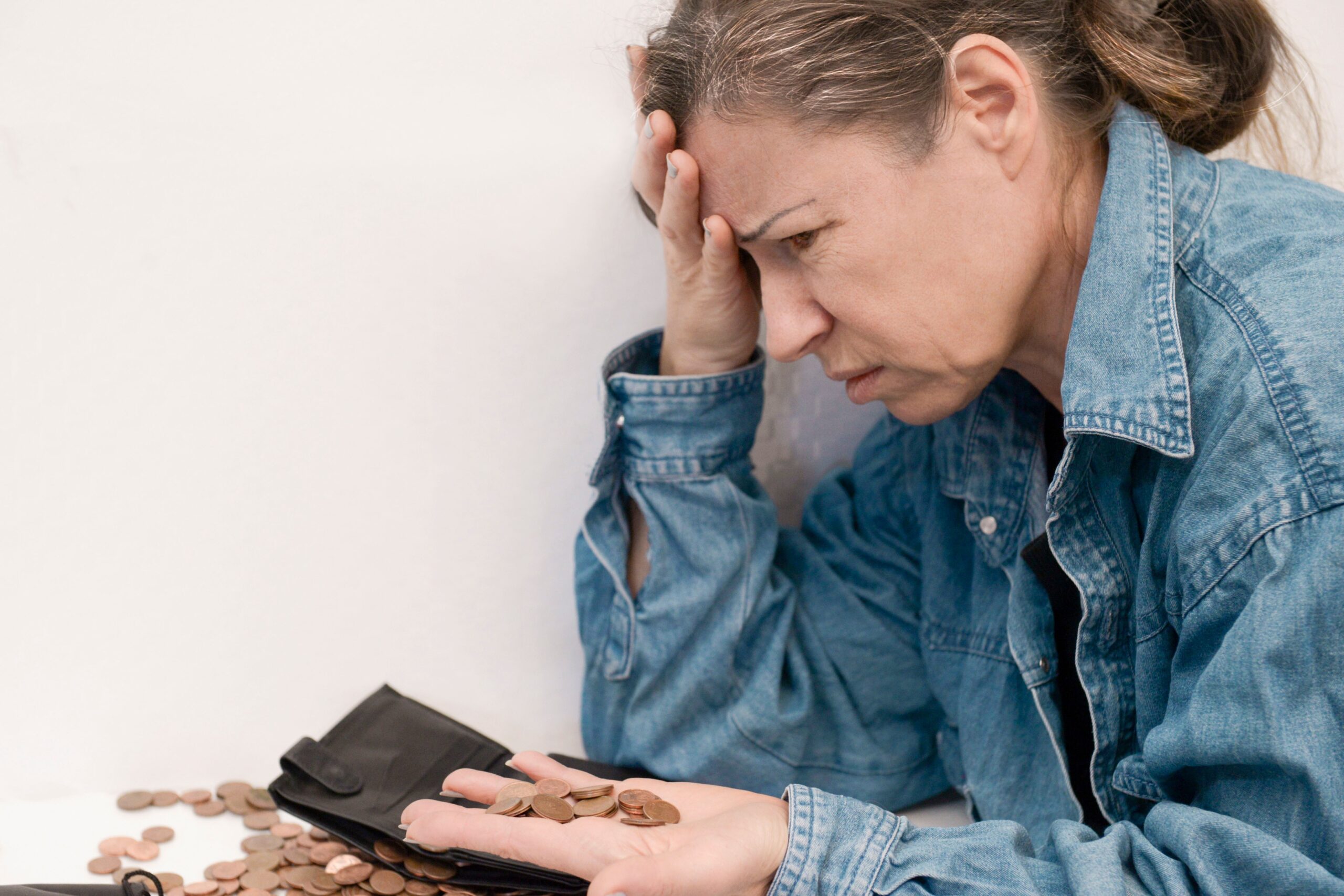 an elderly woman in old age with emotions of stress holds small euro coins in her palm
