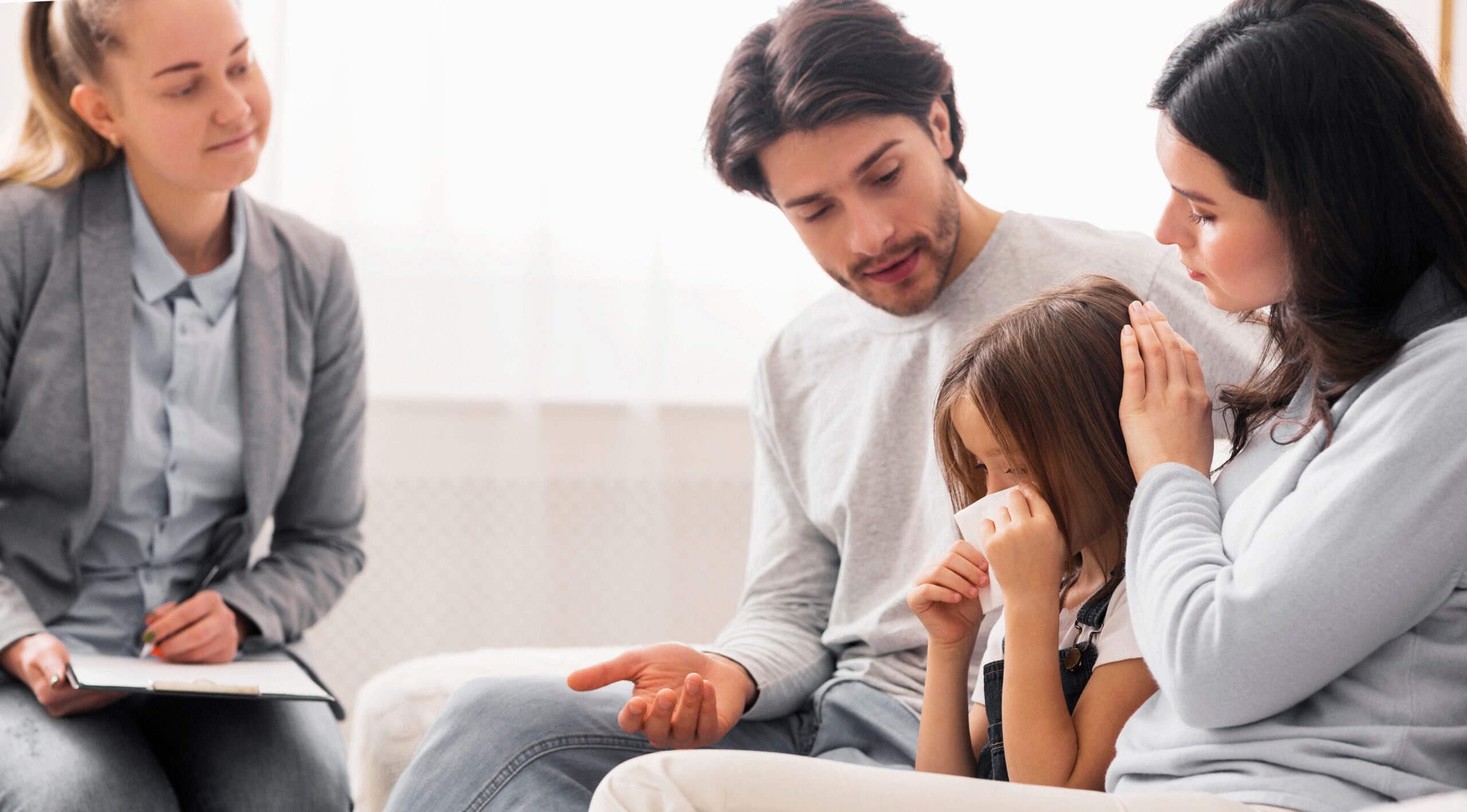 Caring parents comforting their little crying daughter at children psychologist's office