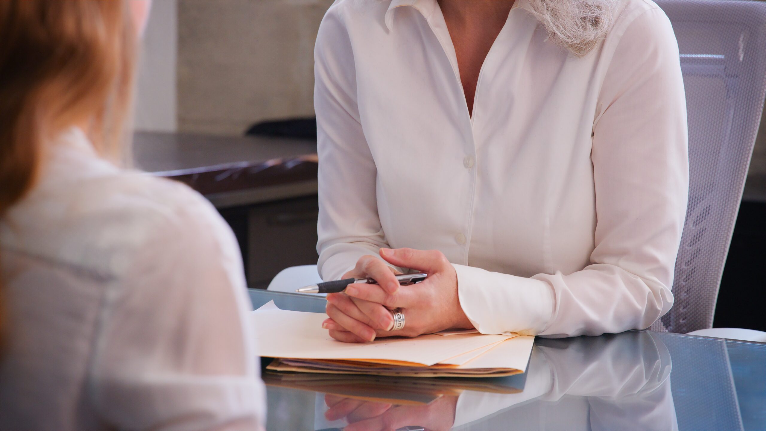 Close Up Of Hands Of Businesswoman Behind Desk Meeting With Female Colleague In Office