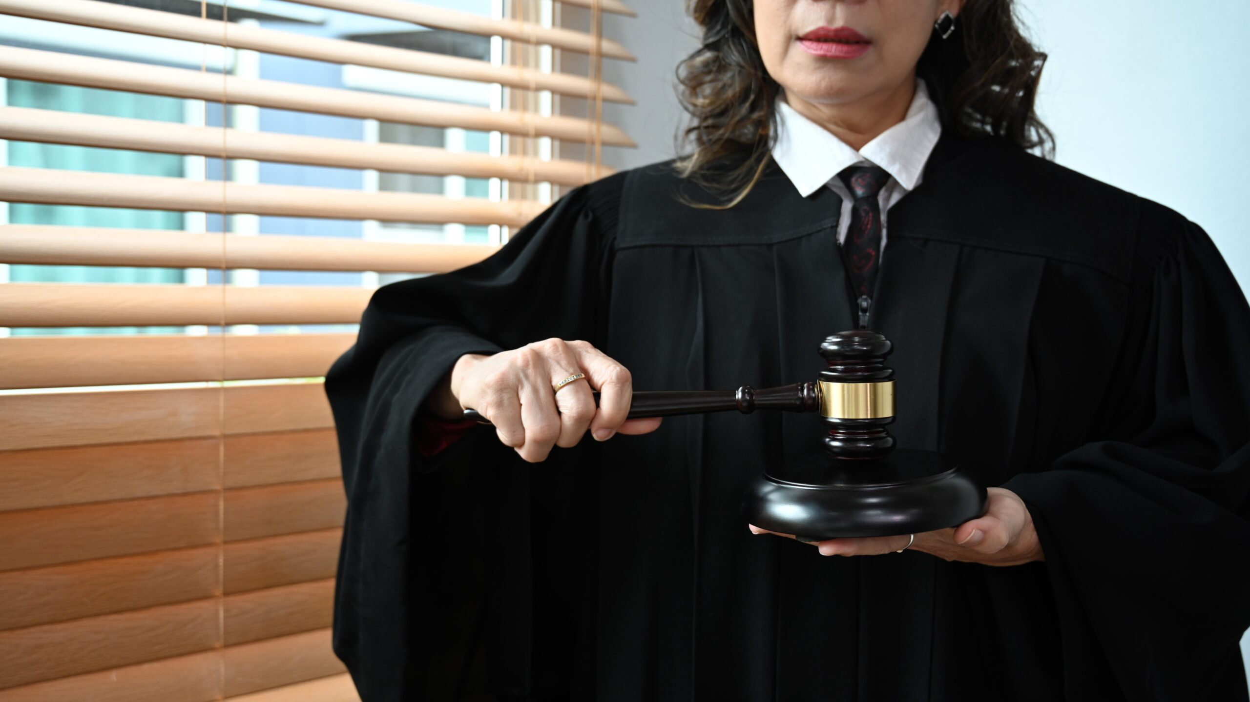 Confident senior judge in robe gown uniform holding a gavel in hands.