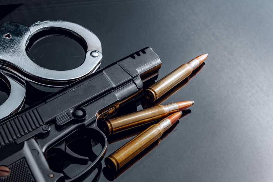 Handcuffs and rifle cartridges on black background