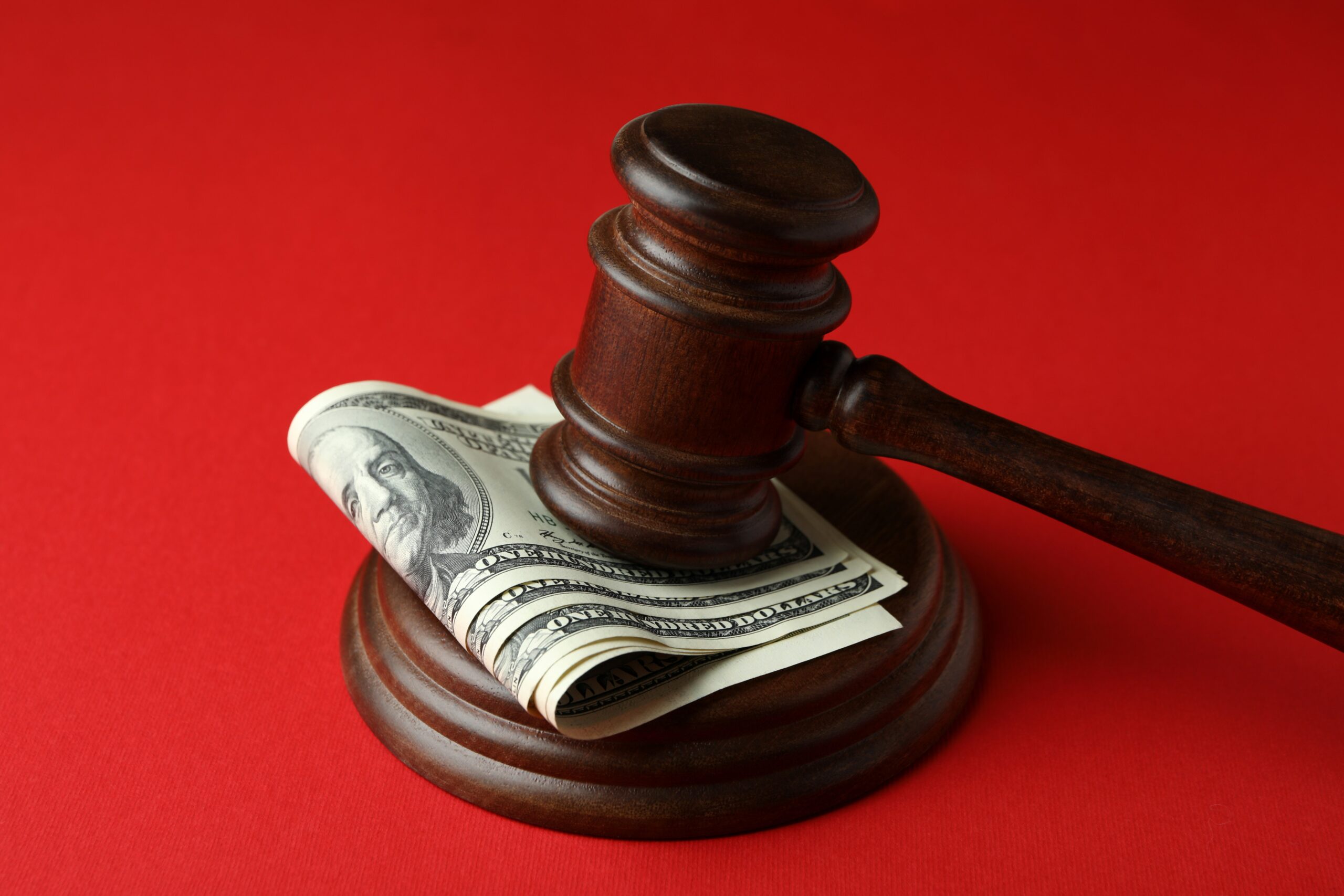 Judge gavel with dollars on red background