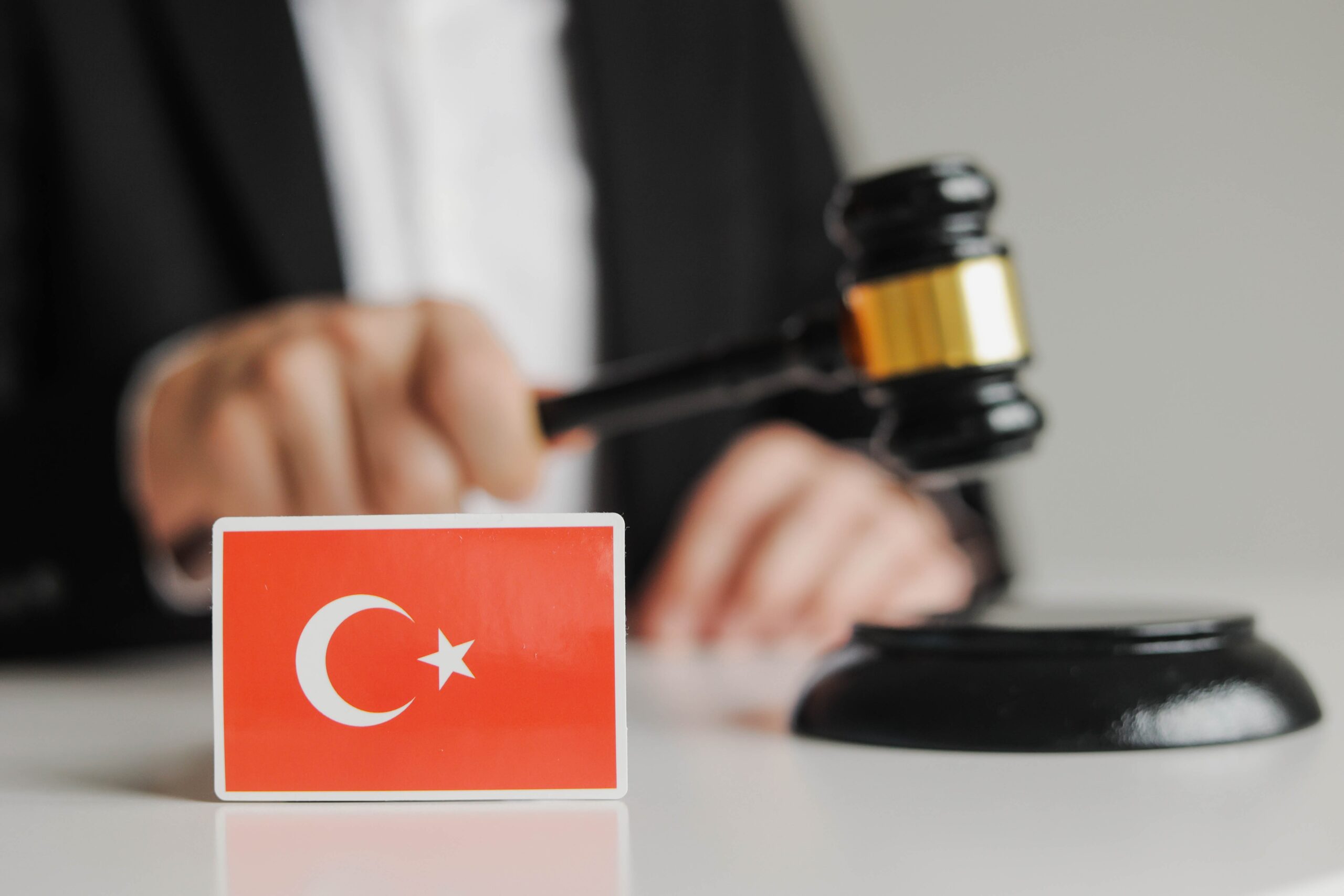 Judge's hand holding wooden gavel. Flag of Turkey. Sanctions in Turkey concept.