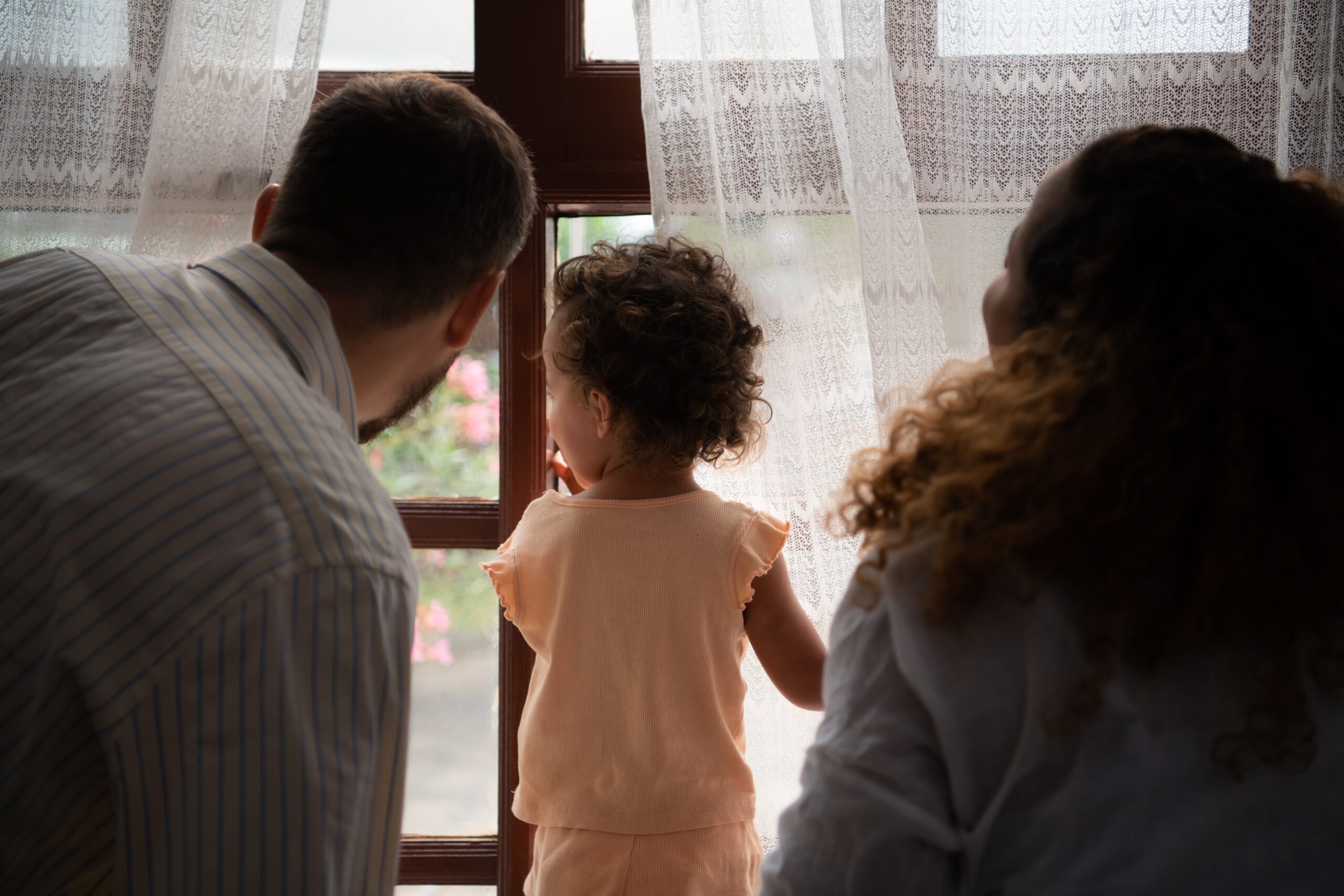 Parents and children enjoy the morning sunlight shining through the bedroom window in the house.