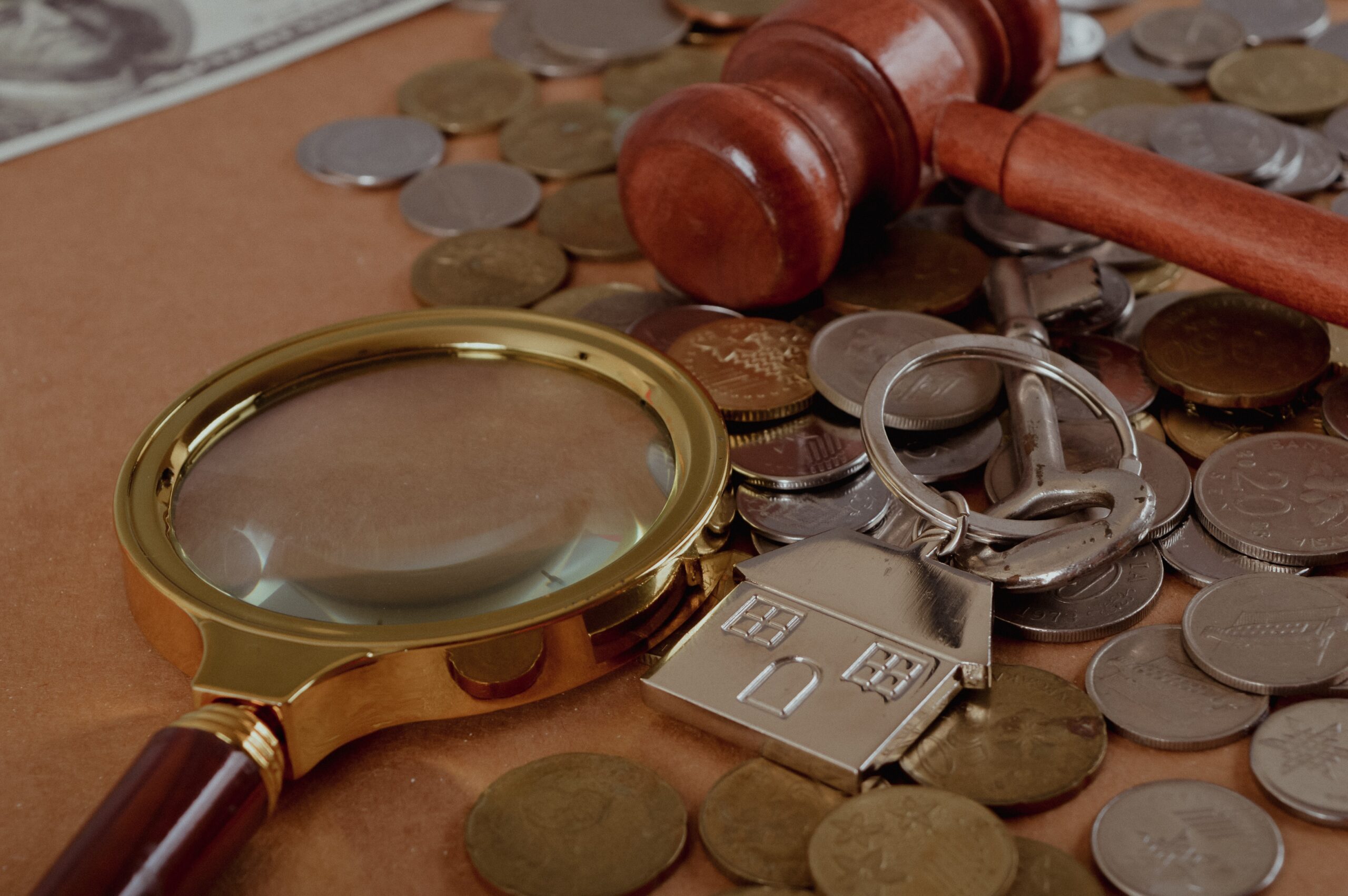 Pile of coins, house keychain, magnifying glass and judge gavel. Real estate auction and law system