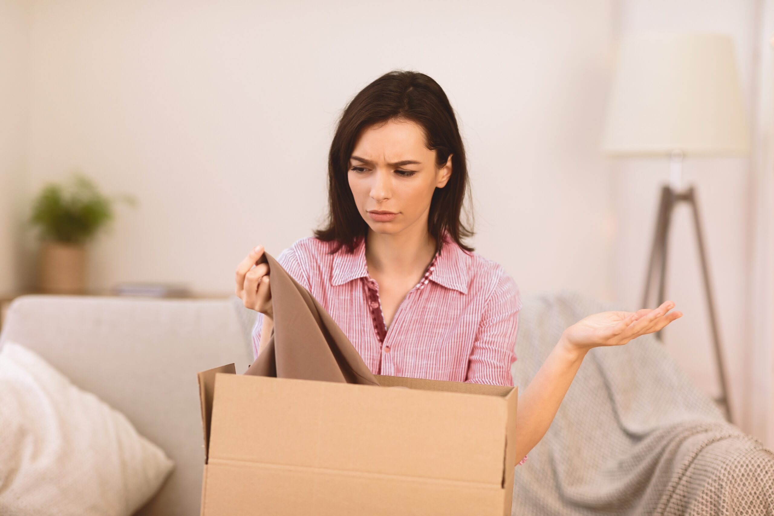 Sad young girl packing clothes for delivery