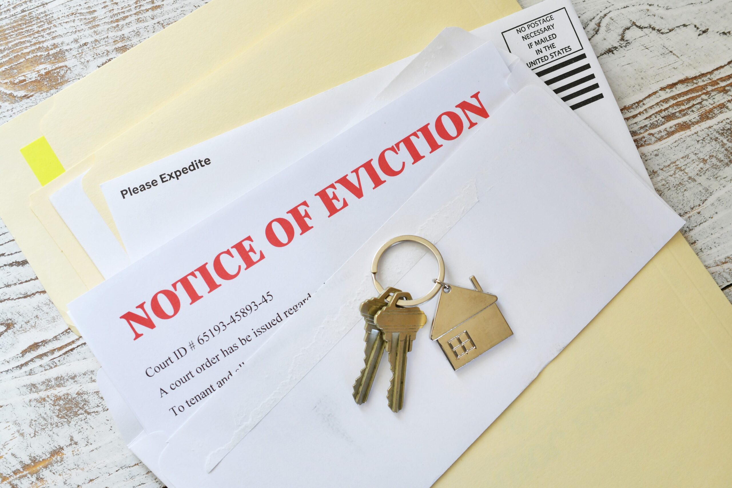 Set of house keys laying on a Eviction notice because someone is behind on the rent.