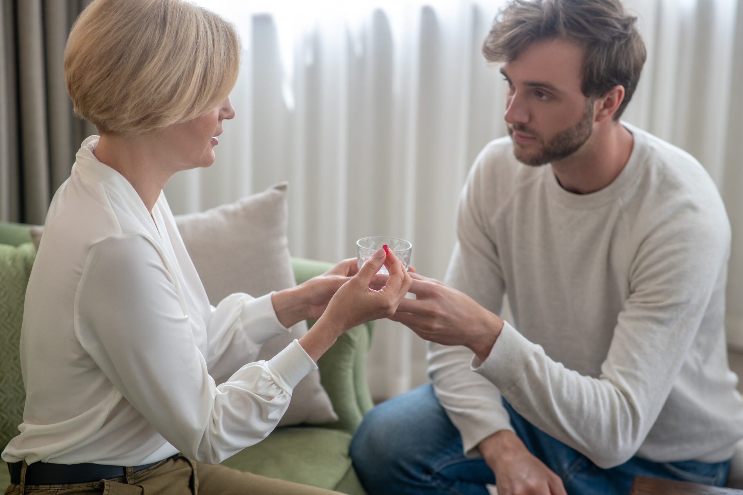 Son giving his mother a glass of water while she feeling unwell