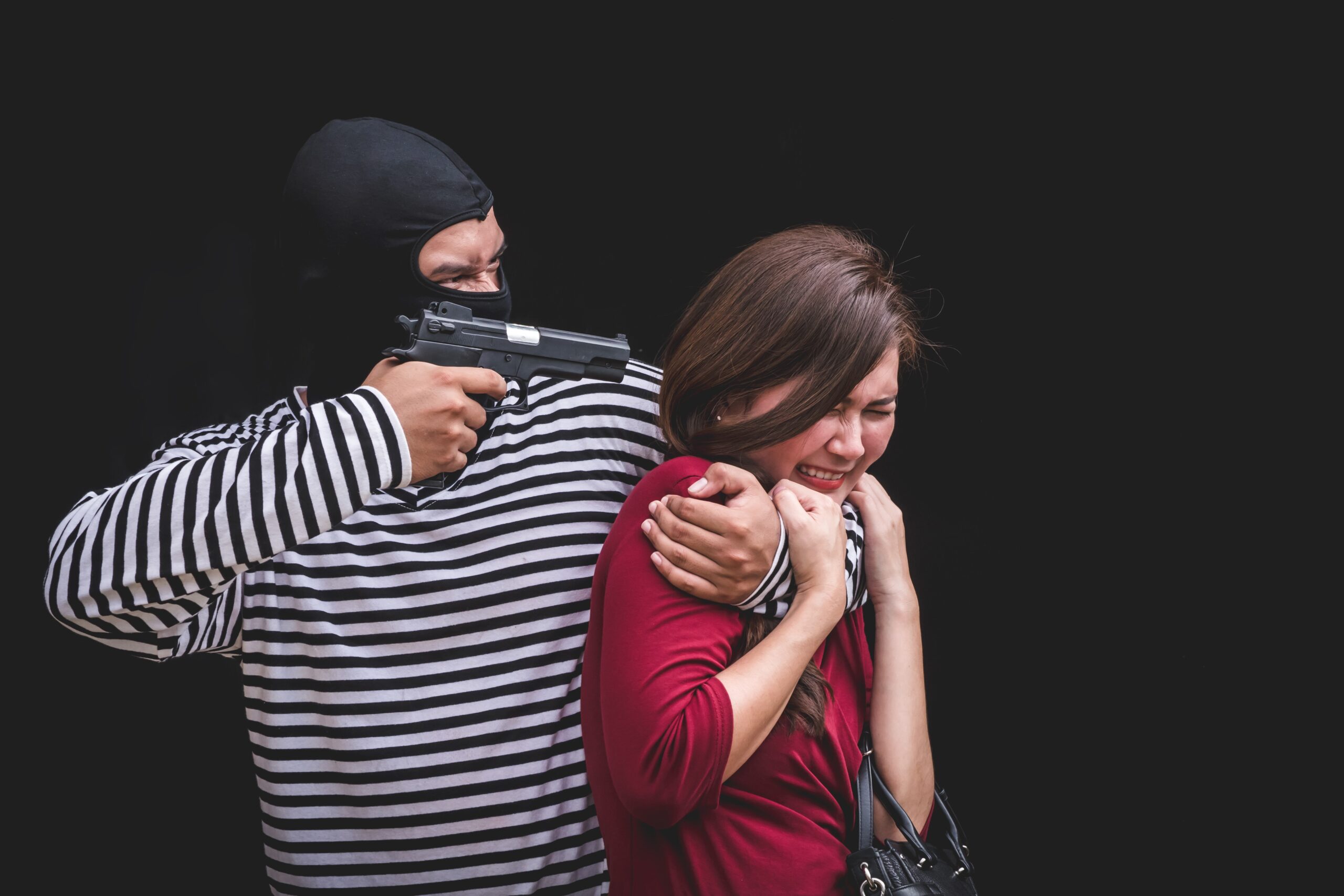 Thief threatening with gun, young woman scared and screaming while arrested by bandit.
