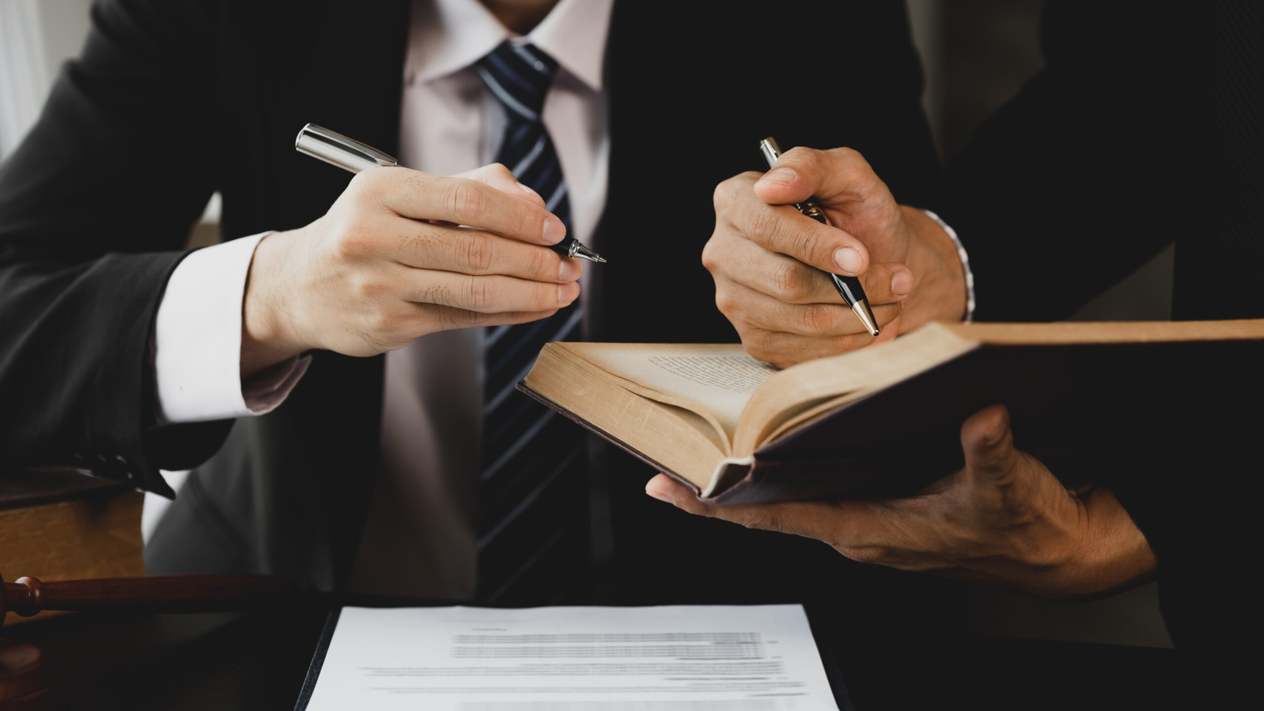 Two lawyers are reading a large book.