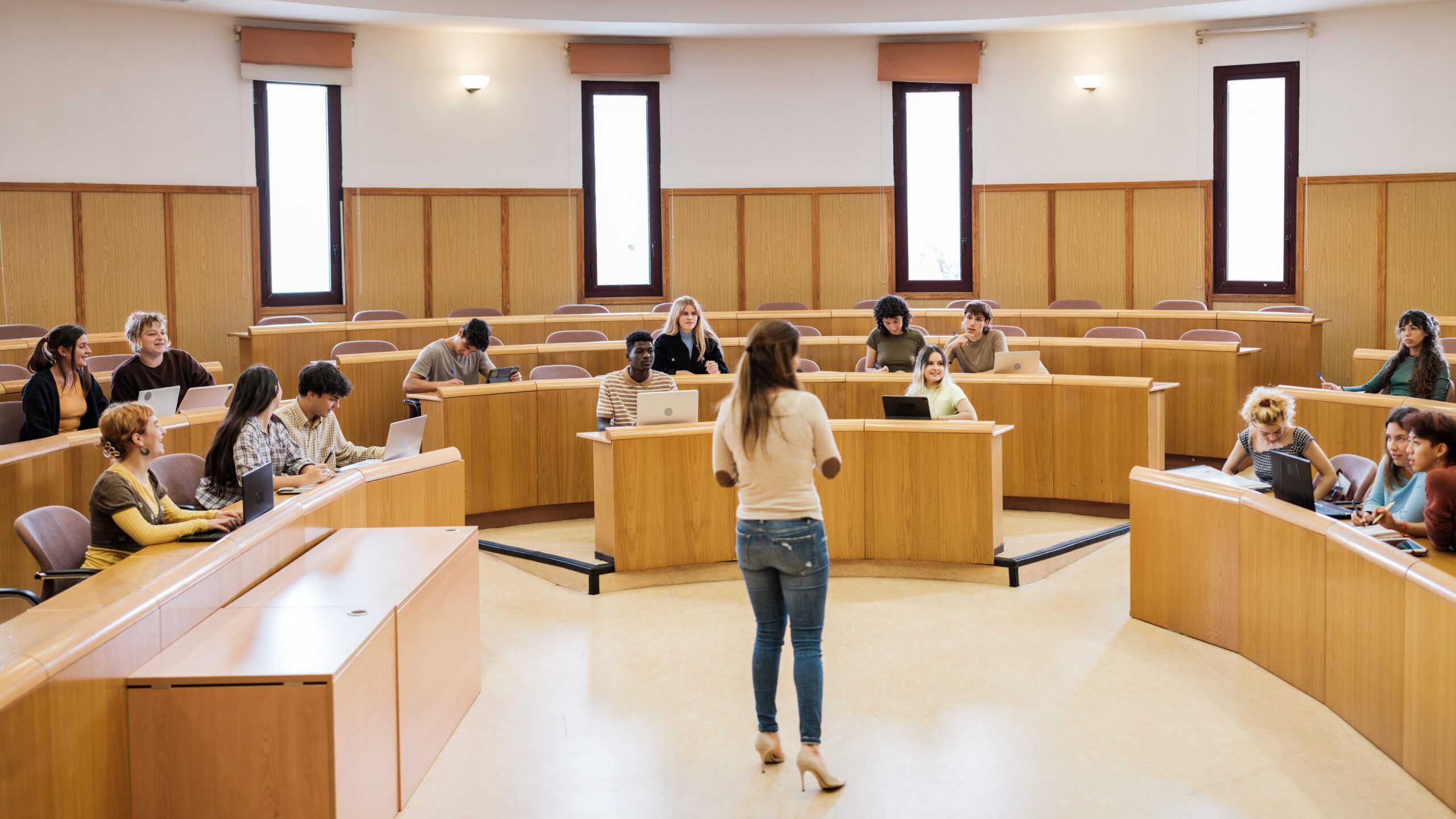 University class in a circular classroom with students of different origins and the teacher