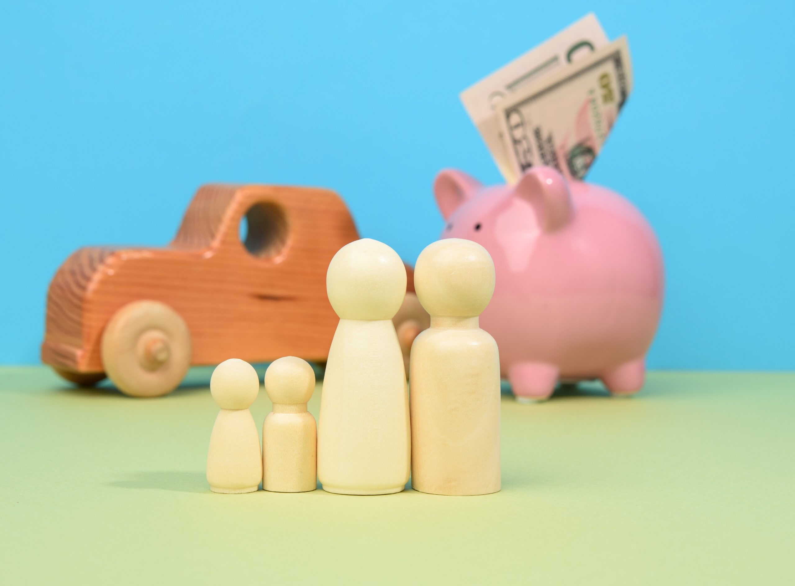 Wooden little men family stands on the background of piggy bank pig and wooden car